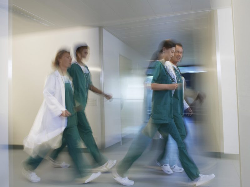 Side view of blurred physicians rushing through hospital corridor