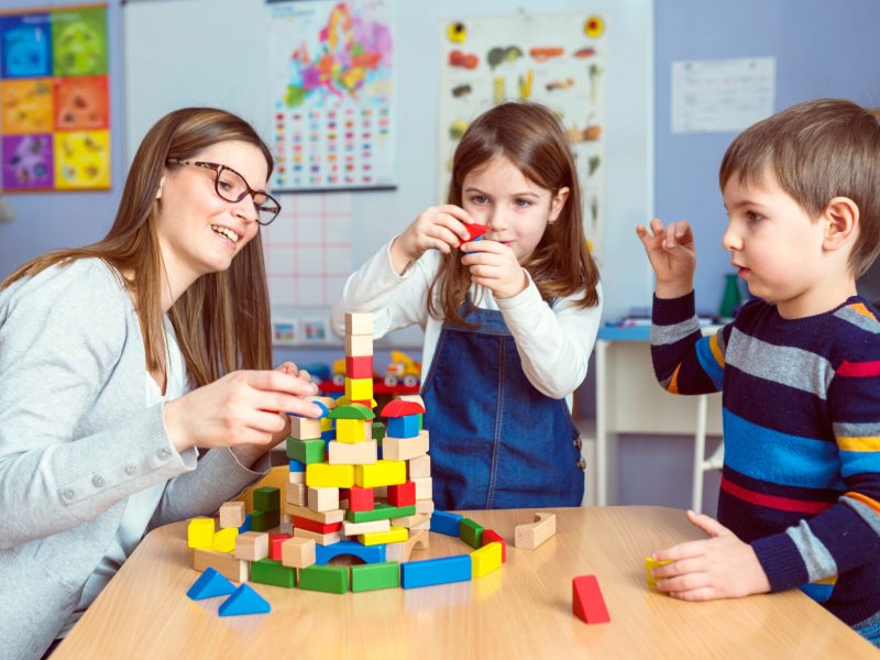 Teacher and Kids Playing Together with Colorful Toy Building Blocks