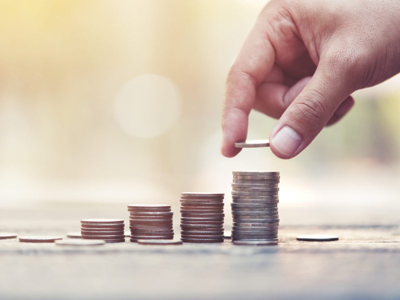 Saving money concept. preset by Male hand putting money coin stack selective focus.