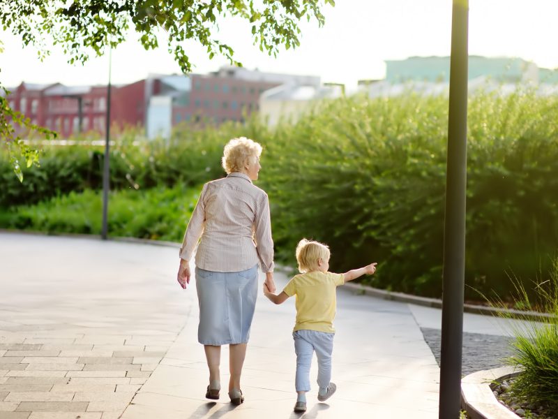 Beautiful granny and her little grandchild walking together in park