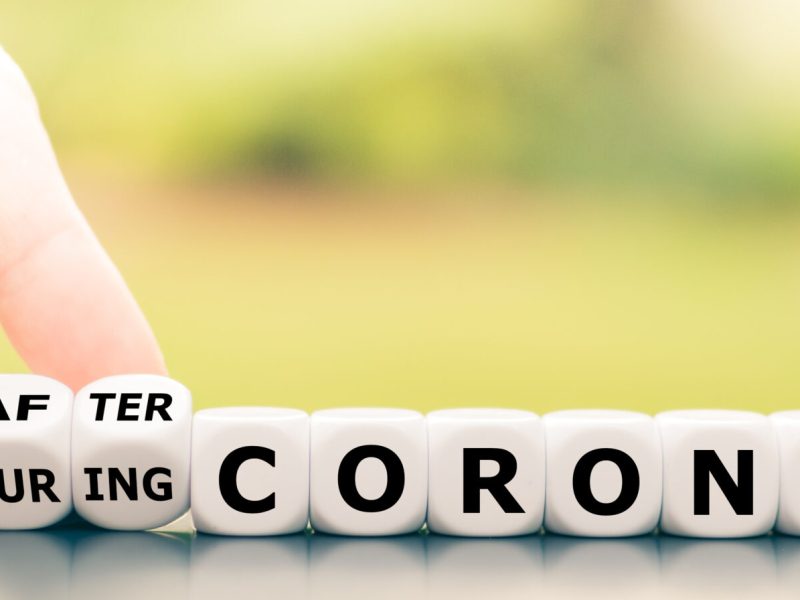 Hand turns dice and changes the expression "during Corona" to "after Corona".