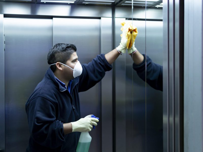 coronavirus. cleaning staff disinfecting elevator to avoid contagion