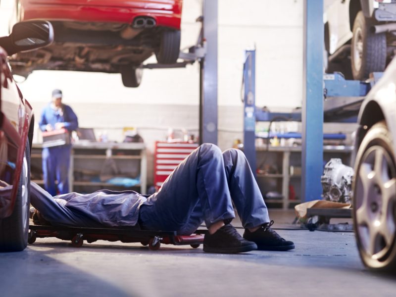 Mechanic under car in auto repair shop