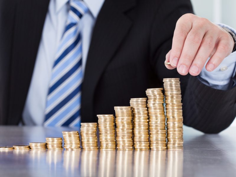 Close-up Of Businessman Hand Put Coins To Stack Of Coins