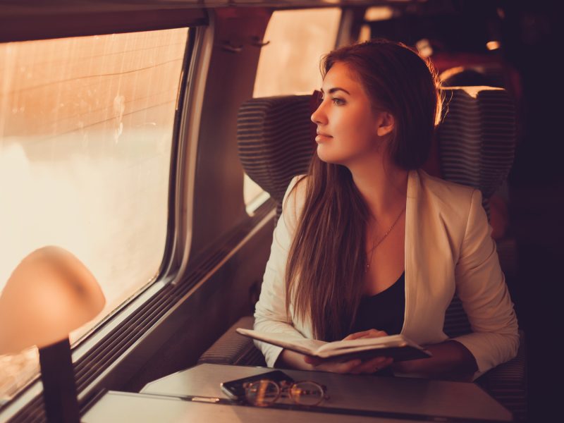 young girl travels on a high-speed comfortable train that runs on a tablet and answer the messages on the phone, surfing on the Internet, outdoor portrait, fashion model, close up