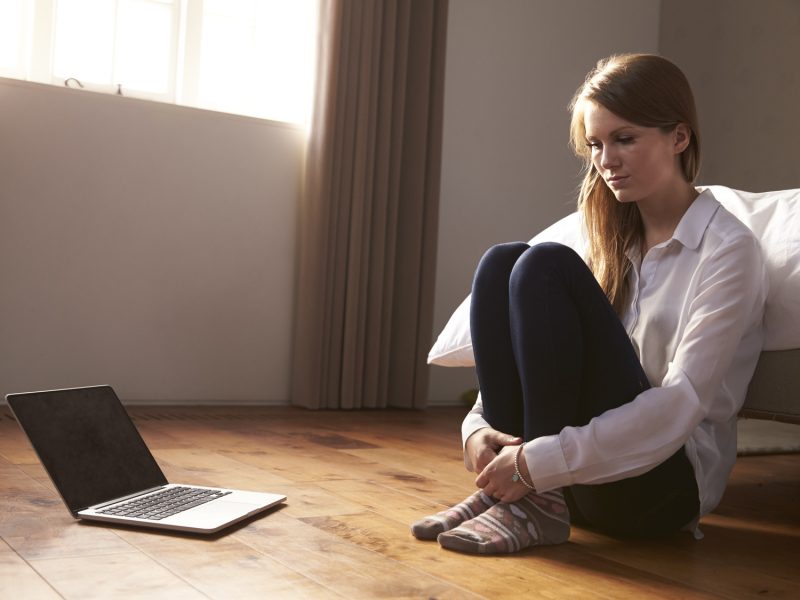 Unhappy Young Woman Being Bullied Online With Laptop