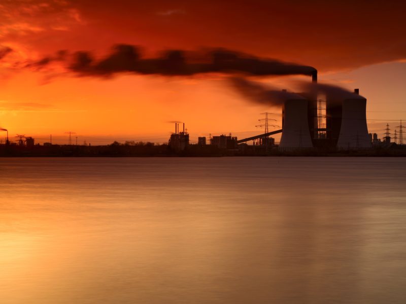 Coal Power Plant on a Lake at Sunrise, Exhaust Fumes blown by Storm, long exposure