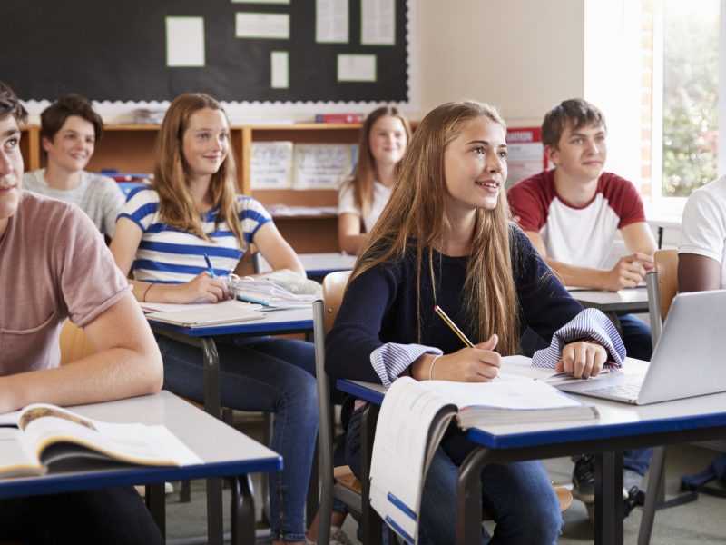 Students Listening To Female Teacher In Classroom