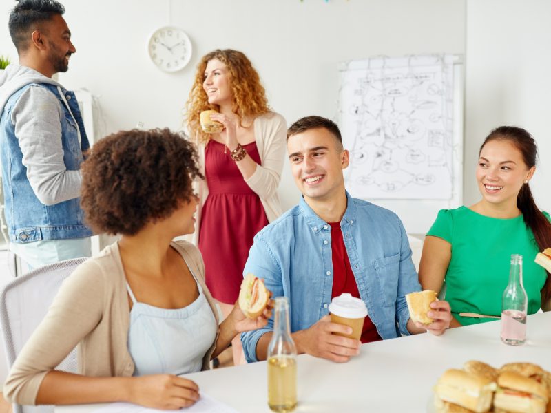 happy friends or team eating at office