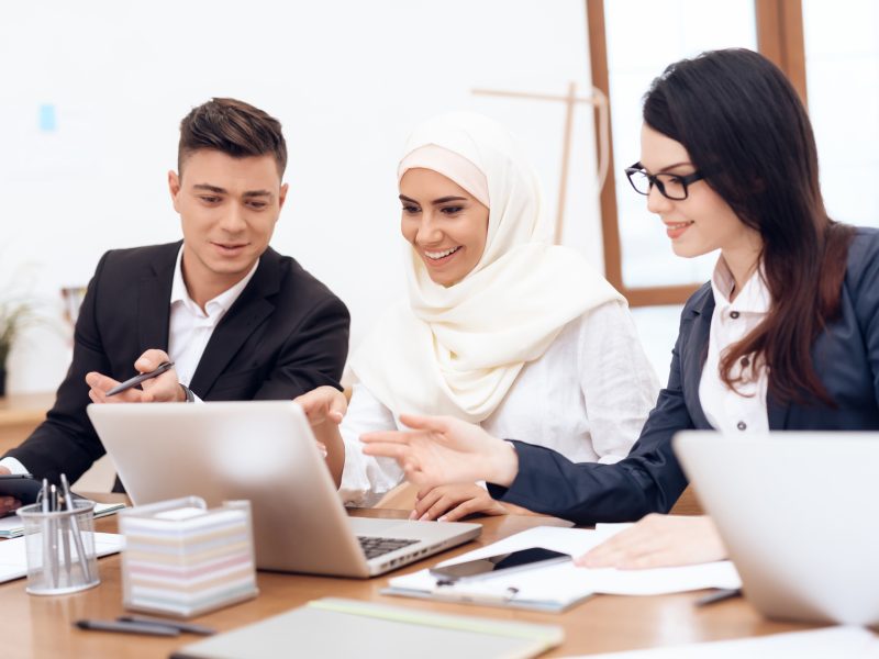 The Arab woman in hijab works in the office together with her colleagues.