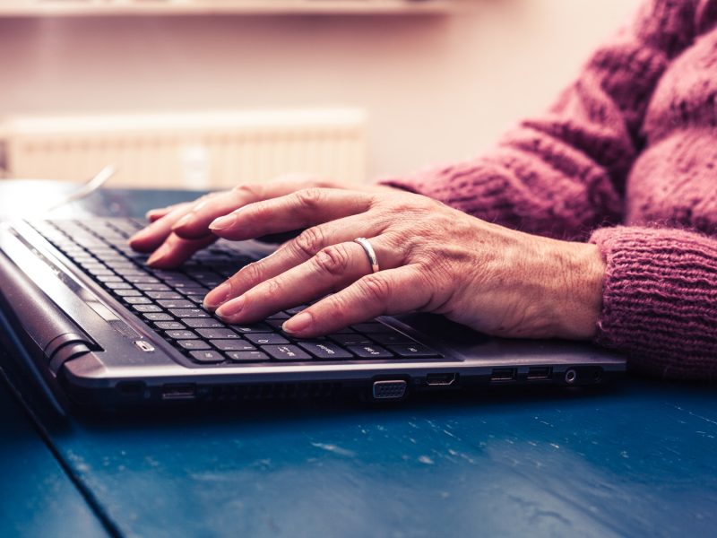 Old woman working on laptop computer at home