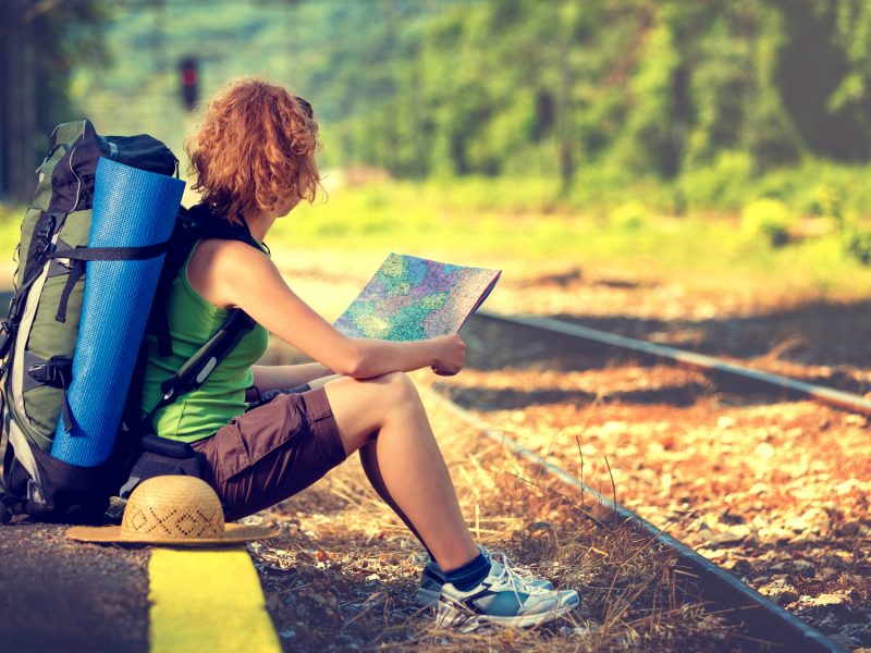 Girl wearing backpack and holding map, waiting for a train.