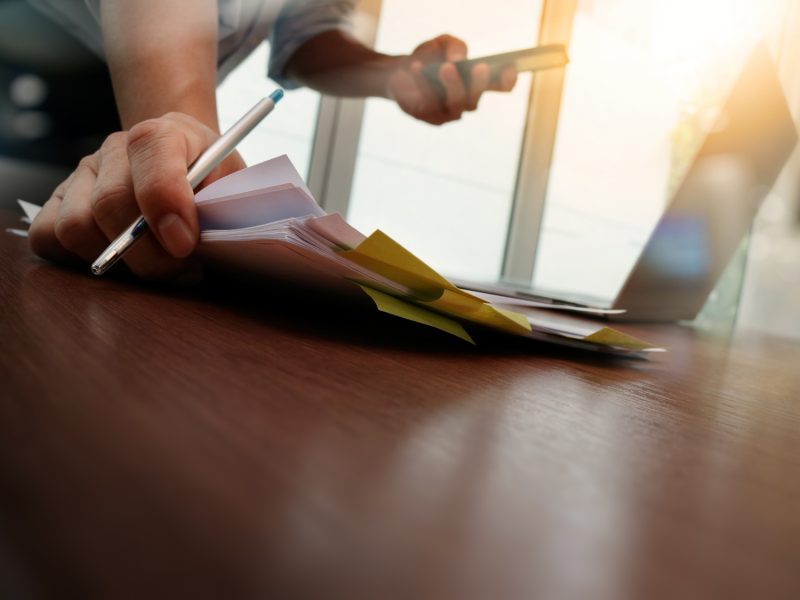 designer hand working and smart phone and laptop on wooden desk