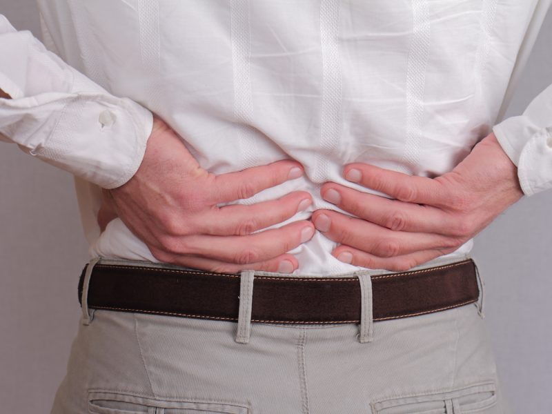 Close up of business man holding his lower back.  Man rubbing his painful back