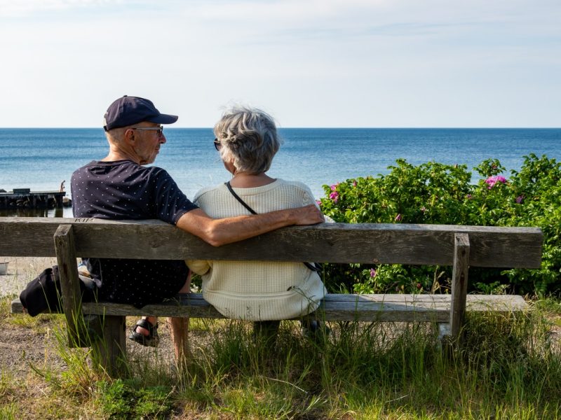 Tisvilde, Denmark May 25, 2024 A senior couple look out to sea while sitting on a bench on the beach.