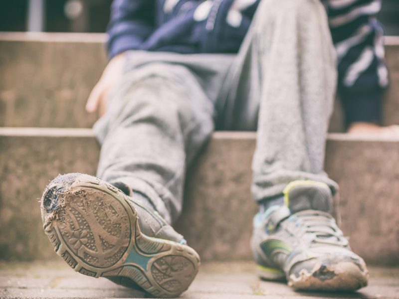 Old broken shoes of a little boy as a symbol for child poverty