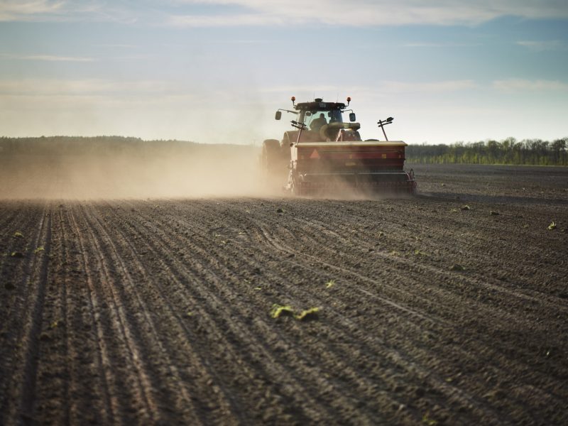 Red tractor with sowing machine on a ploughed field