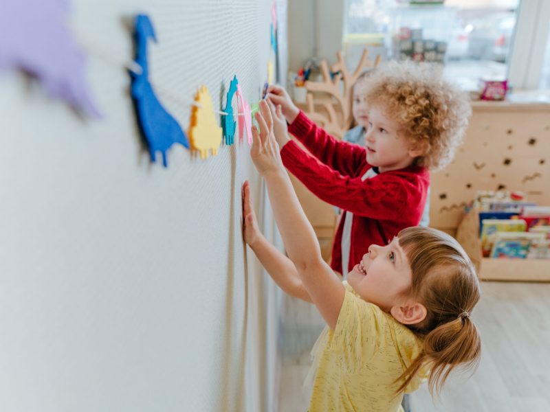 Preschool students playing in kindergarten with color dinosaur figures