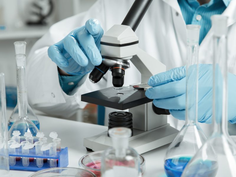 men in a laboratory microscope with microscope slide in hand