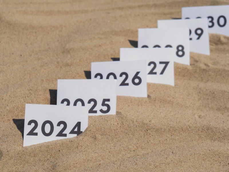 Paper cards with numbers of years from 2024 to 2030 in a row. New year start concept. Resolution time is flying plan goal motivation