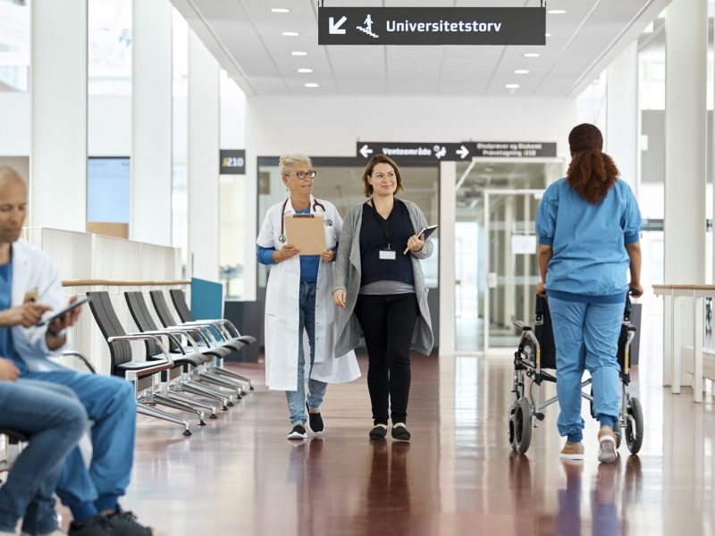 Doctors And Patient In Hospital Corridor